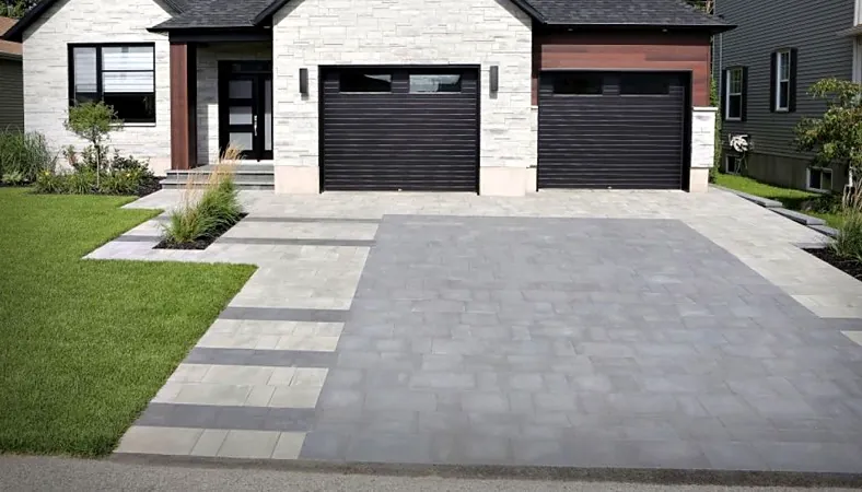 Grey interlock driveway with a darker border, leading to a two-car garage