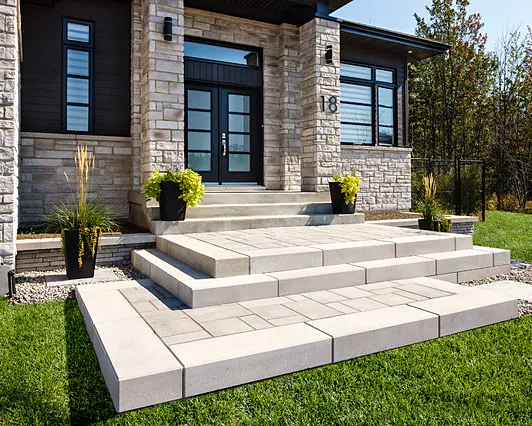 Wide precast front steps and landing in front of a stone house